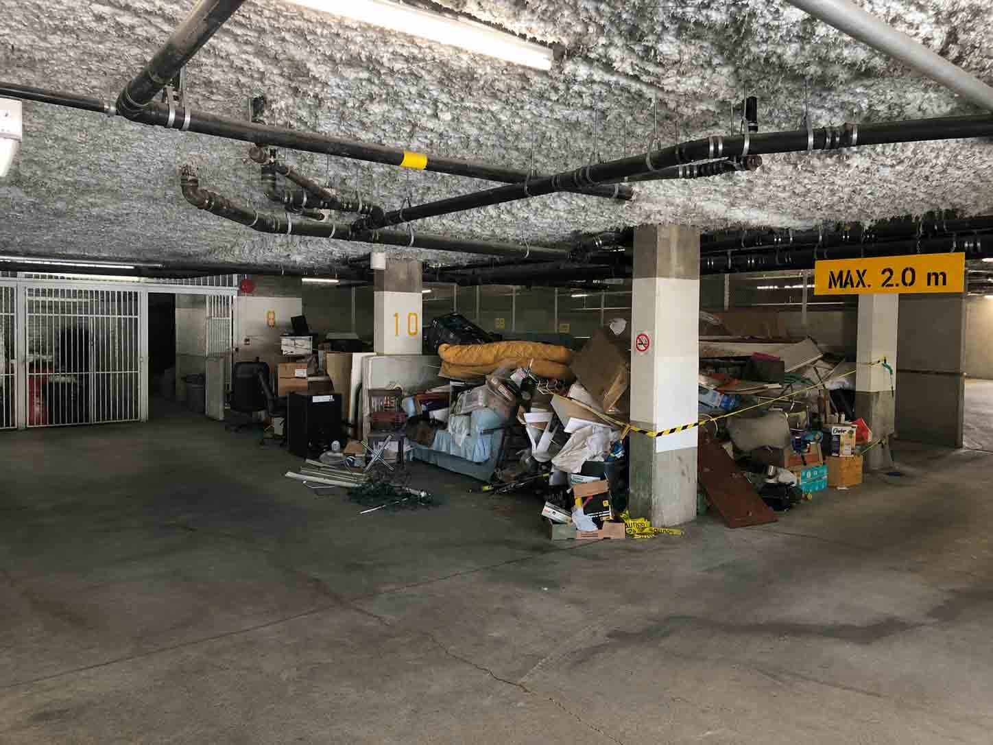 Pile of furniture, boxes, and unwanted items in underground parking before cleanout by Turbo Haul Disposal